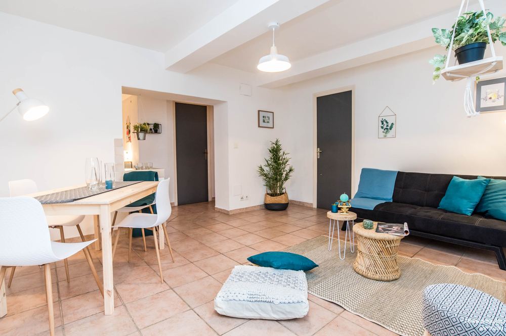 Pièce de vie mise en scène par Magalie Lala : table dressée, canapé et coussins bleu canard, plantes