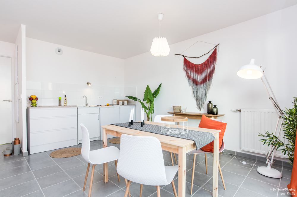 Cuisine ouverte mise en scène avant la mise en vente : table dressée, plantes et luminaires
