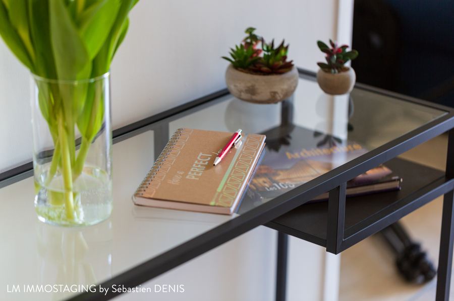 Console en verre avec bouquet de tulipes, plantes grasses et carnets, détail d'une mise en scène