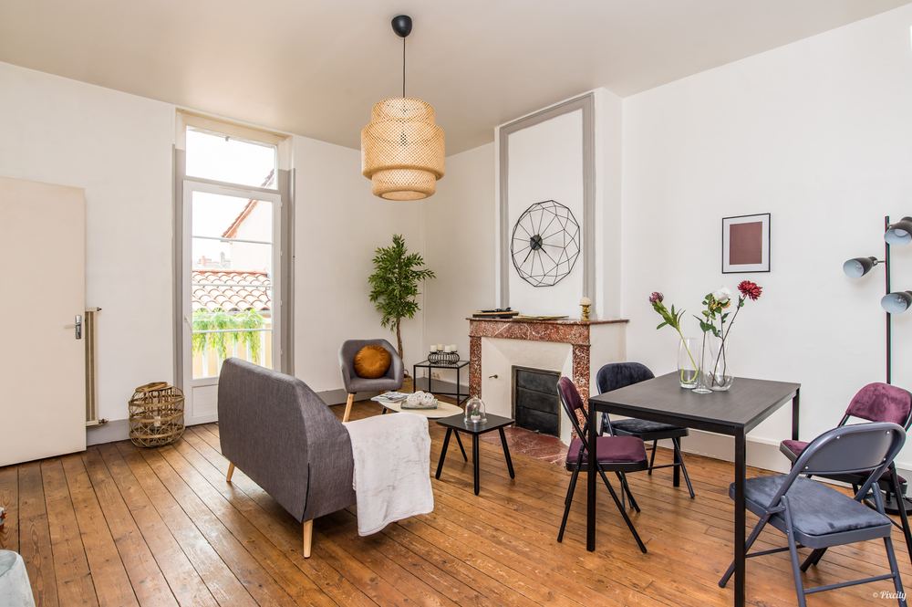 Salle à manger mise en scène : parquet, cheminée et table dressée devant la fenêtre
